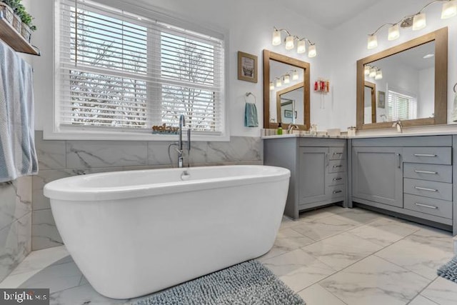 bathroom with vanity, tile walls, and a bathtub