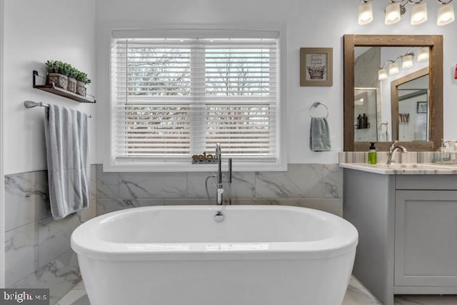 bathroom with vanity, tile walls, and a bathing tub