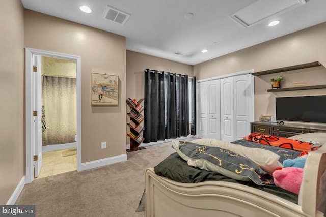 bedroom featuring a closet, connected bathroom, and light carpet