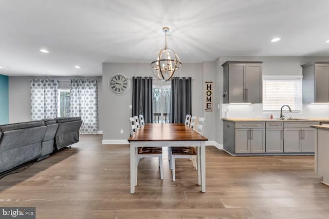 dining area featuring sink, a notable chandelier, and light hardwood / wood-style floors