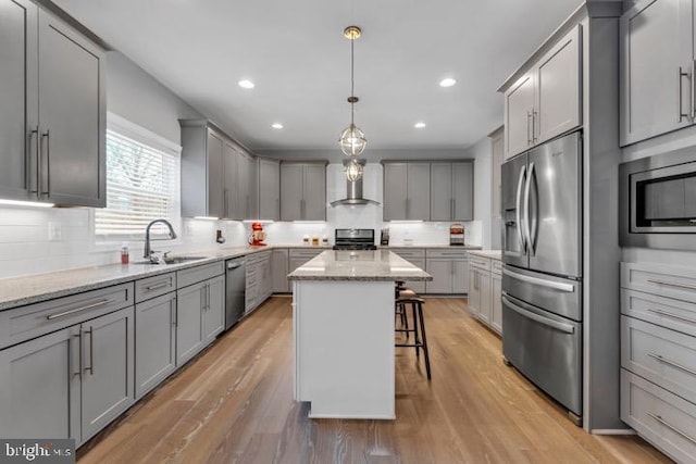 kitchen featuring sink, a breakfast bar area, gray cabinets, a kitchen island, and stainless steel appliances