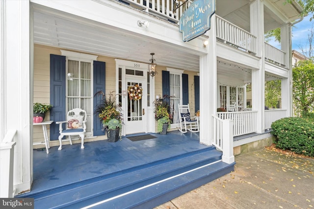 view of exterior entry with a porch and a balcony