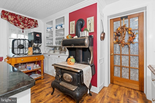 interior space featuring dark wood-type flooring, built in shelves, a textured ceiling, and a wood stove