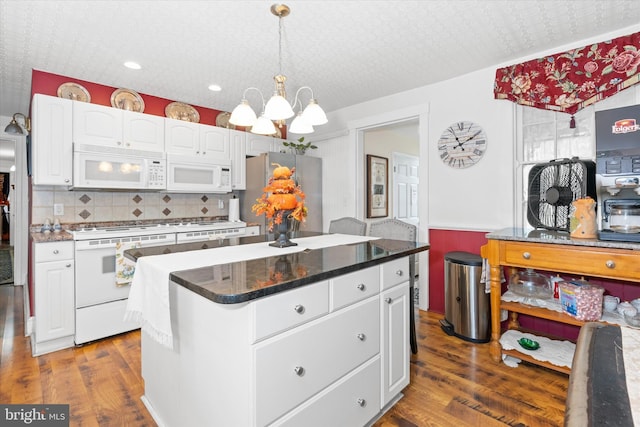 kitchen with a center island, hanging light fixtures, dark hardwood / wood-style flooring, white appliances, and white cabinets