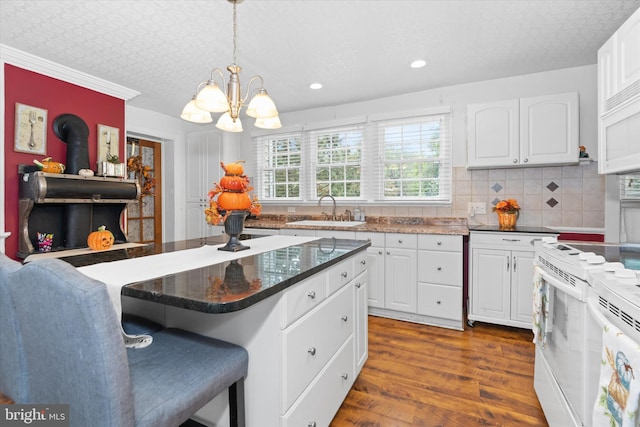 kitchen with pendant lighting, white cabinetry, sink, a kitchen breakfast bar, and white appliances