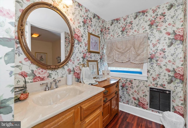 bathroom with hardwood / wood-style floors, vanity, heating unit, and a fireplace