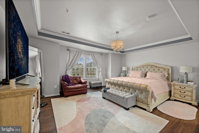 bedroom featuring hardwood / wood-style flooring, ornamental molding, an inviting chandelier, and a tray ceiling