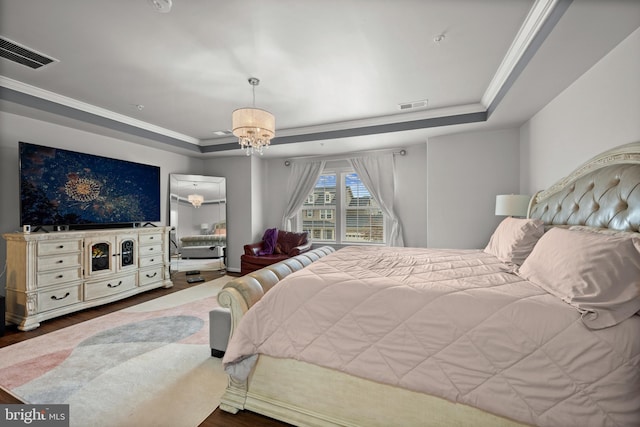 bedroom featuring crown molding, an inviting chandelier, a raised ceiling, and hardwood / wood-style floors