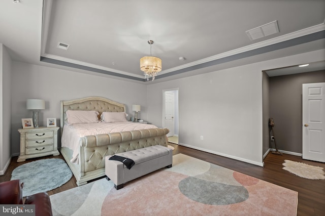 bedroom with an inviting chandelier, dark hardwood / wood-style floors, and a raised ceiling