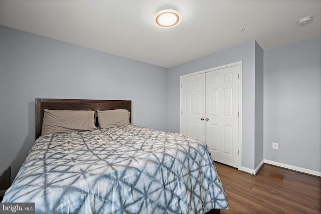 bedroom with dark wood-type flooring and a closet