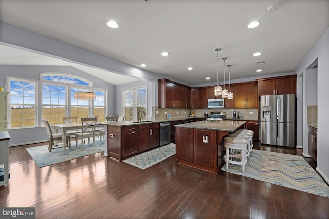 kitchen with hanging light fixtures, stainless steel appliances, sink, and a kitchen island