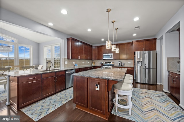 kitchen with stainless steel appliances, a kitchen island, sink, and a kitchen bar