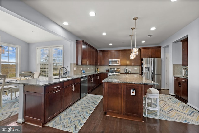 kitchen featuring sink, hanging light fixtures, a center island, kitchen peninsula, and stainless steel appliances