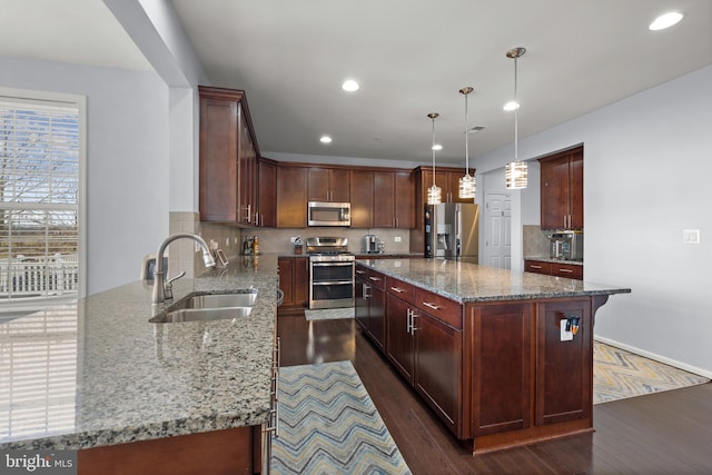 kitchen with appliances with stainless steel finishes, a center island, sink, and light stone countertops