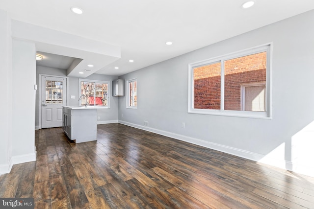 unfurnished living room with dark wood-style floors, recessed lighting, bar area, and baseboards