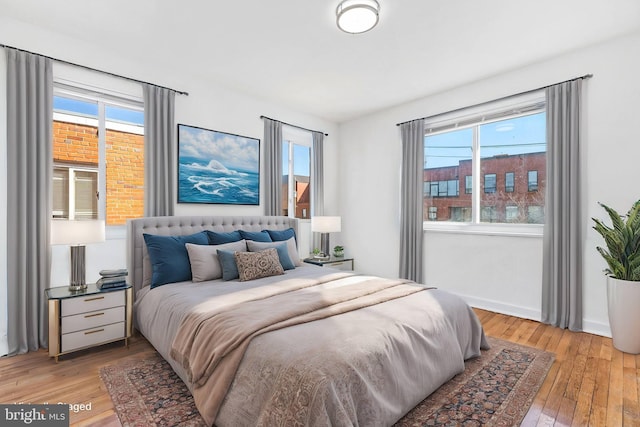 bedroom featuring baseboards, multiple windows, and light wood-style floors