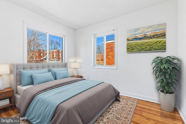 bedroom featuring multiple windows, wood finished floors, and baseboards