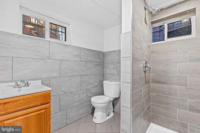 full bathroom featuring tile walls, toilet, a tile shower, vanity, and tile patterned flooring