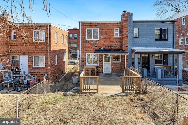 back of house featuring a fenced backyard, a chimney, cooling unit, and brick siding