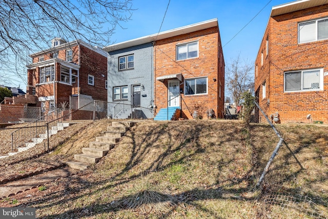 rear view of property featuring brick siding and fence