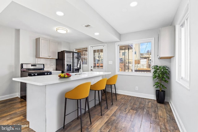 kitchen featuring tasteful backsplash, appliances with stainless steel finishes, light countertops, and baseboards