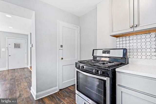 kitchen with light stone counters, dark wood finished floors, backsplash, gas stove, and white cabinets