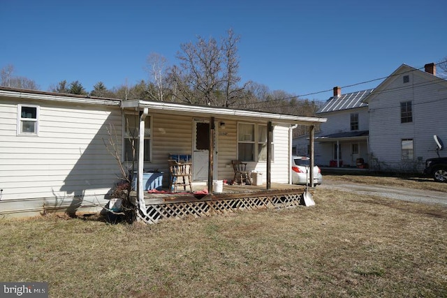 rear view of property featuring covered porch and a yard