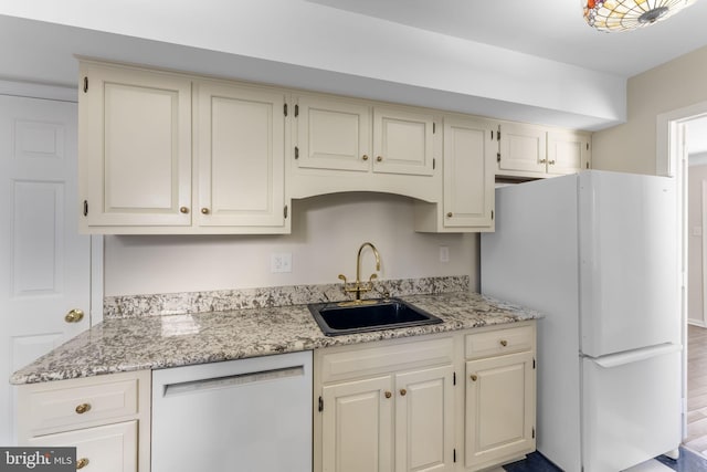 kitchen featuring white appliances, sink, and light stone countertops