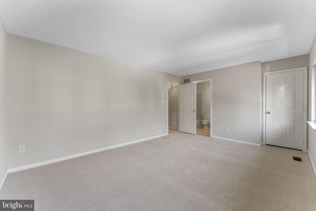 unfurnished bedroom with light carpet and connected bathroom