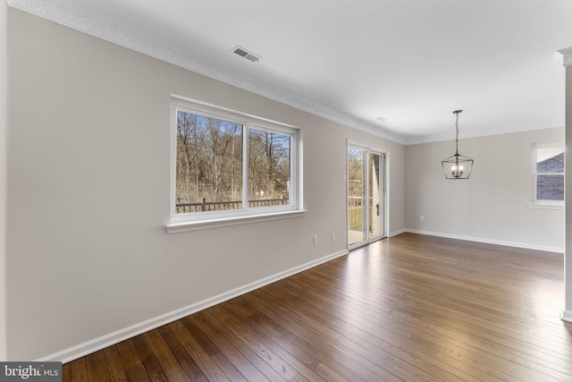 empty room featuring hardwood / wood-style flooring, crown molding, and an inviting chandelier