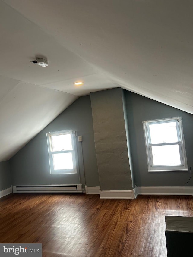 bonus room with dark wood-type flooring, a baseboard radiator, and vaulted ceiling