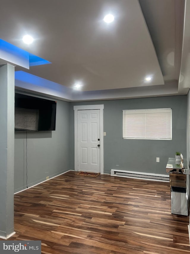 basement featuring dark wood-type flooring and a baseboard radiator