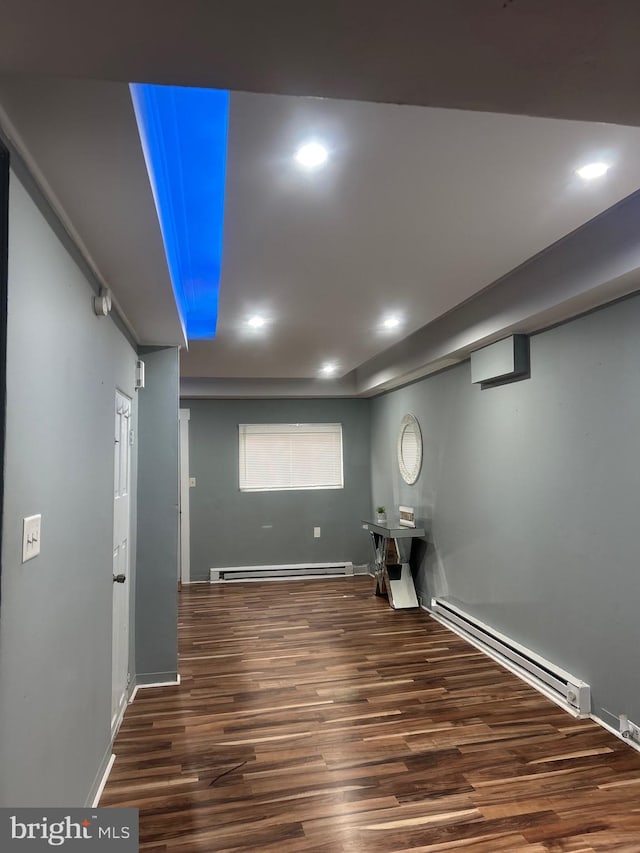 interior space with dark wood-type flooring and a baseboard heating unit