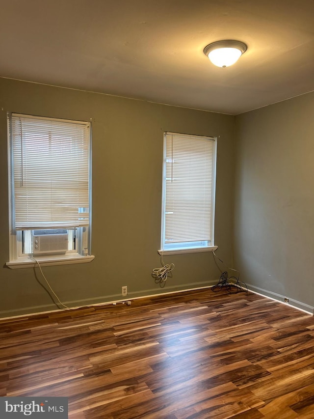 unfurnished room with a healthy amount of sunlight, dark wood-type flooring, and cooling unit