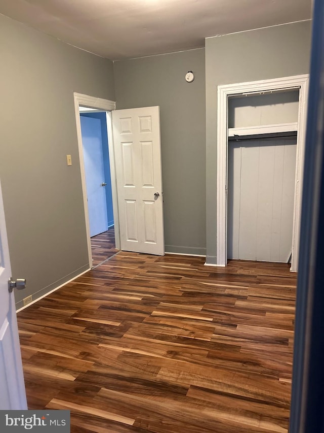 unfurnished bedroom with dark wood-type flooring and a closet