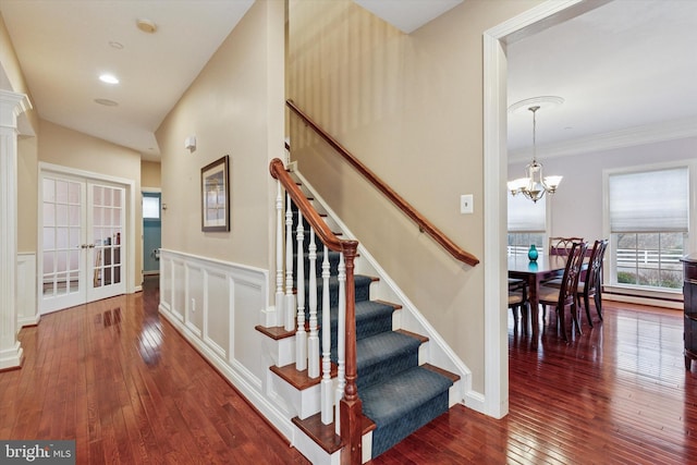 staircase featuring ornamental molding, french doors, an inviting chandelier, and hardwood / wood-style flooring