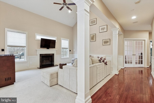 living room featuring decorative columns, a premium fireplace, wainscoting, ceiling fan, and carpet flooring