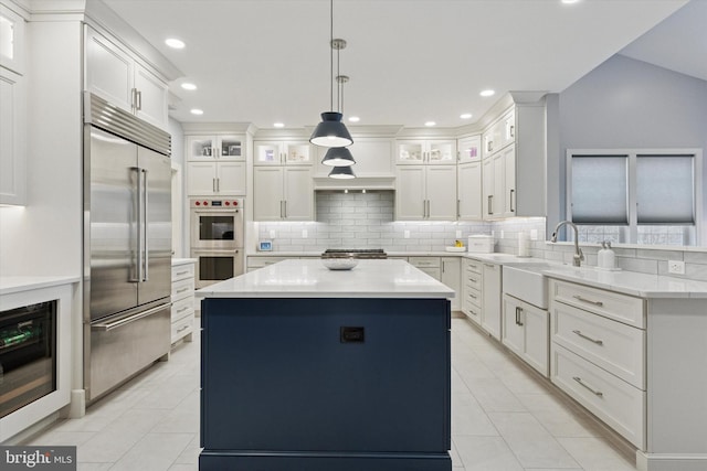 kitchen with stainless steel appliances, backsplash, white cabinetry, a sink, and a kitchen island