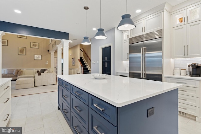 kitchen with decorative columns, a kitchen island, open floor plan, built in refrigerator, and blue cabinets