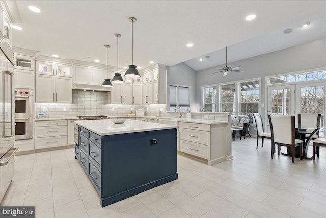 kitchen featuring light countertops, a peninsula, backsplash, and a center island