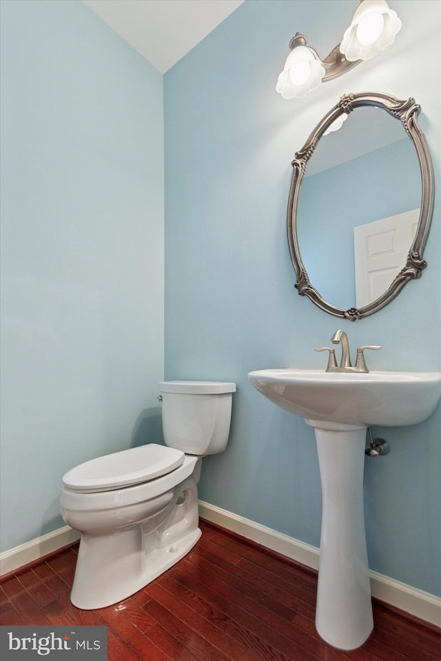 bathroom with baseboards, toilet, and hardwood / wood-style floors