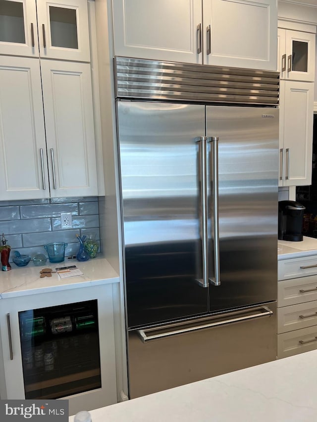 kitchen featuring wine cooler, stainless steel built in refrigerator, glass insert cabinets, and white cabinets