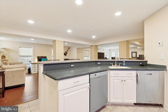 kitchen with open floor plan, stainless steel dishwasher, dark countertops, and a sink