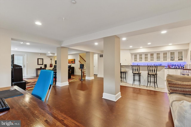 interior space with recessed lighting, wood finished floors, bar, baseboards, and stairs