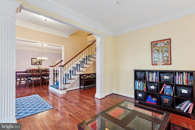 sitting room with hardwood / wood-style flooring, ornamental molding, stairway, decorative columns, and an inviting chandelier