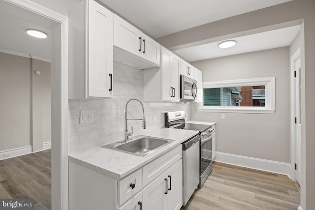 kitchen with sink, white cabinetry, tasteful backsplash, light wood-type flooring, and stainless steel appliances