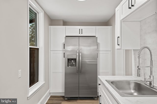 kitchen with white cabinetry, sink, stainless steel fridge, light stone counters, and dark wood-type flooring