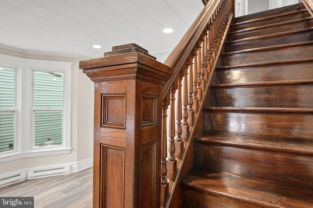 stairway with wood-type flooring and a baseboard heating unit