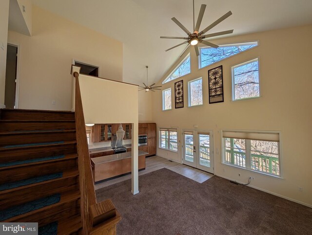 carpeted living room with high vaulted ceiling, french doors, and ceiling fan