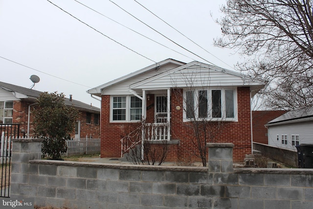 bungalow-style home featuring a fenced front yard and brick siding